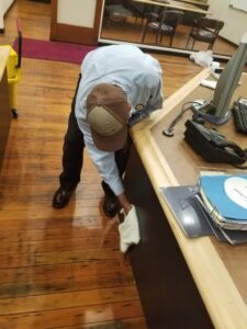 Commercial Cleaner wiping down desk in office building